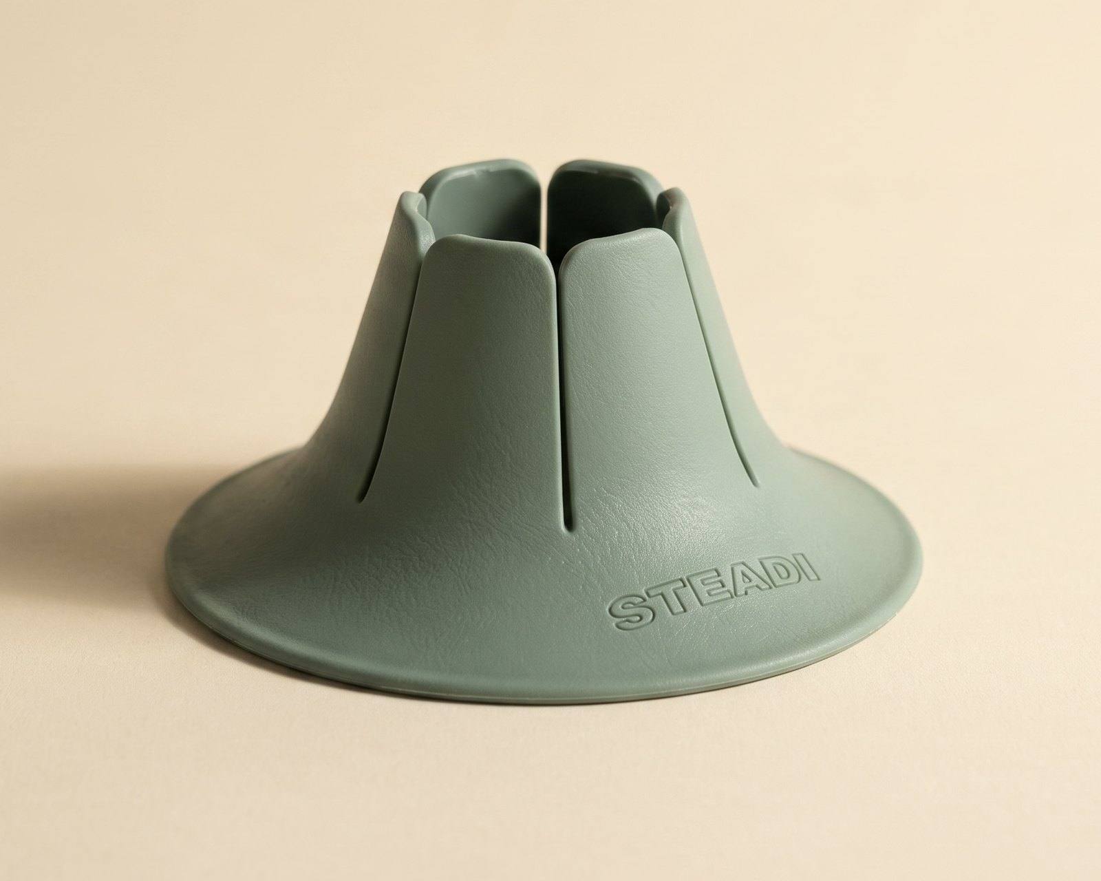 A sage drink holder photographed on warm paper.