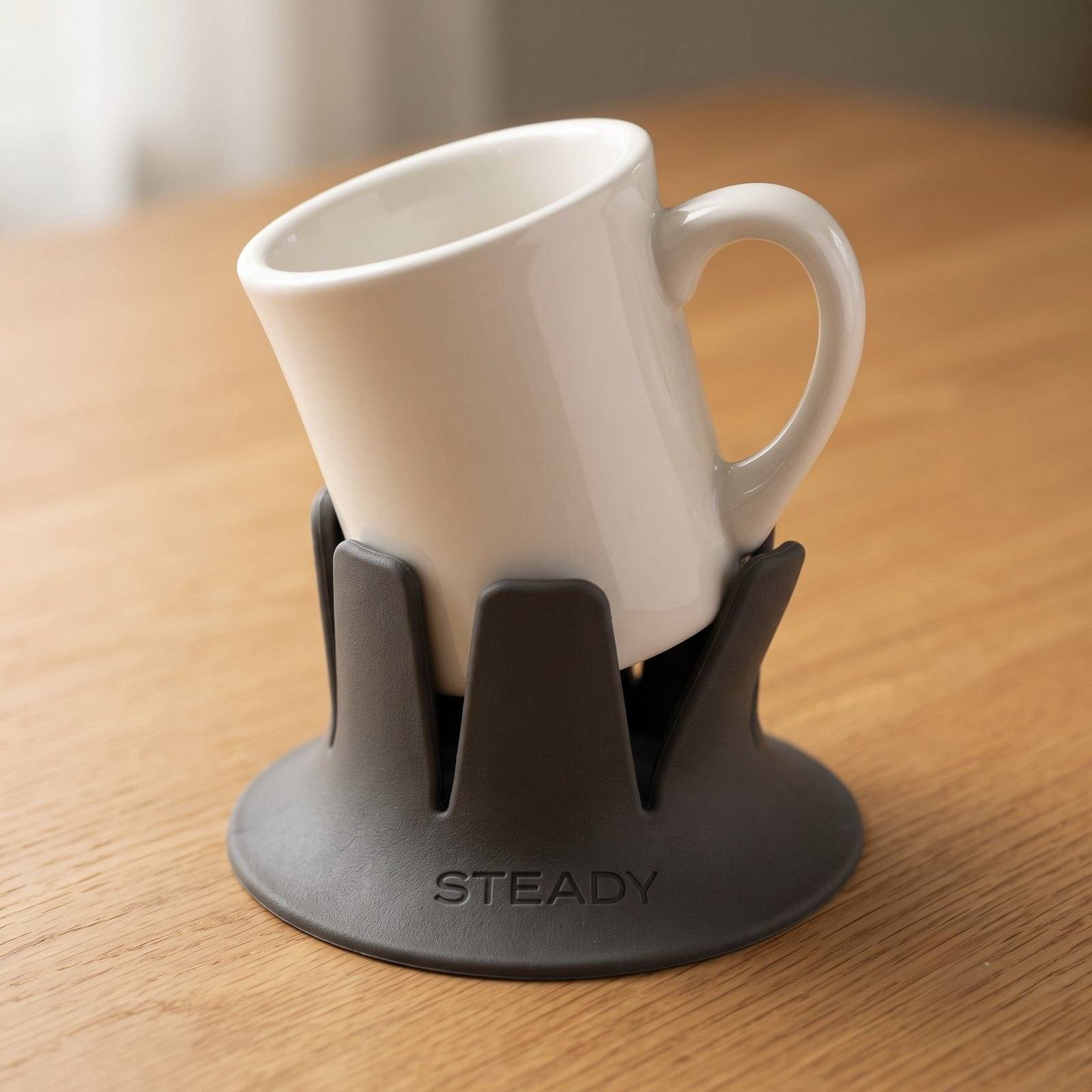 A handled coffee mug sitting tilted in the holder, its handle propped on a fin and blocking it from seating.