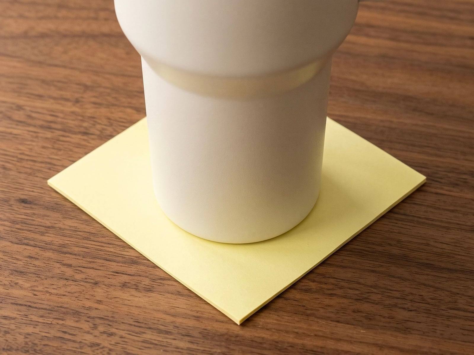 A 40 oz tumbler's base sitting just inside a 3-inch sticky note on a walnut table.