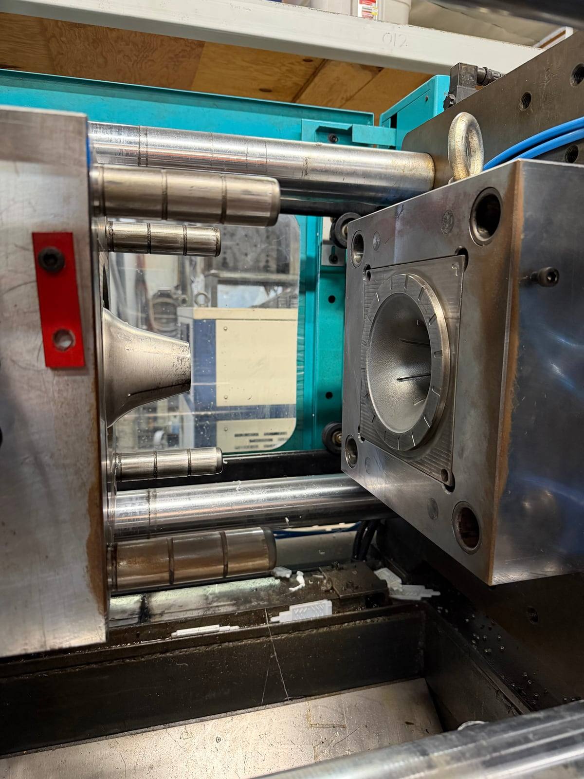 The injection mold open inside the machine: the cavity plate above, the product-shaped steel core below.