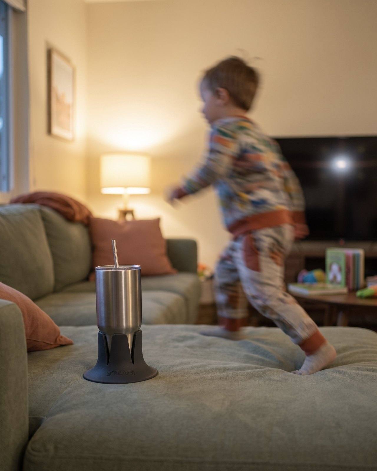 A child running past while a tumbler stays steady in the holder on the couch.